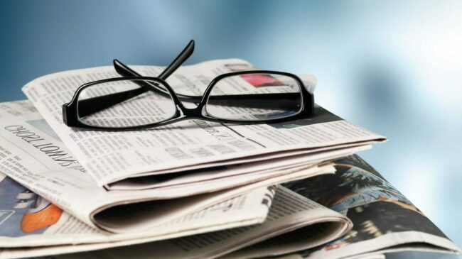 Pile of newspapers stacks and glasses on blur background